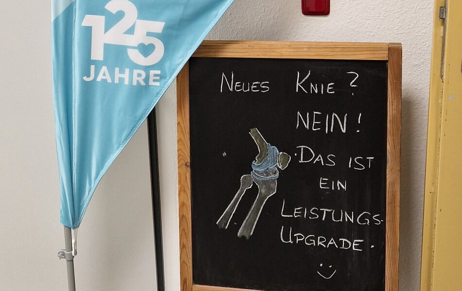 Tafel mit einer Zeichnung des Kniegelenks und dem Hinweis „Neues Knie? Nein! Das ist ein Leistungs-Upgrade“ beim Orthopädie-Vortrag in Sonneberg.